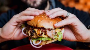 Young man eating a cheeseburger.