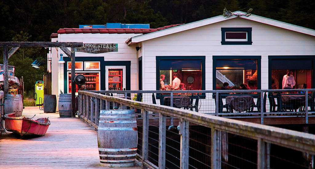 A boat docked at Nick's Cove with a restaurant in the background.