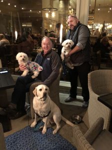 A group of men at Carmel Valley Ranch sitting in chairs with their dogs.