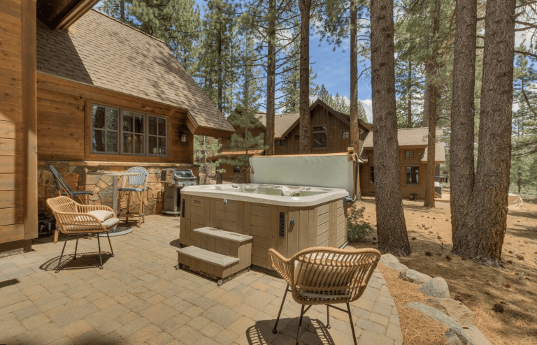 A vibrant dog park bathed in sunlight features abundant greenery with mature trees, offering ample shade for leisurely outdoor activities. In the distance is a well-equipped playground that presents an additional activity area. An inviting picnic table spreads out nearby, ideal for enjoying meals al fresco or taking relaxing breaks from play. A neatly-placed trash bin aids in maintaining the park's cleanliness for everyone's enjoyment. Dominating the scene is a generously wide dirt path gracefully curving through the expanse of grass, promising exploratory walks and lively fetch games.