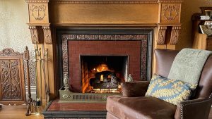 A vibrant dog park bathed in sunlight features abundant greenery with mature trees, offering ample shade for leisurely outdoor activities. In the distance is a well-equipped playground that presents an additional activity area. An inviting picnic table spreads out nearby, ideal for enjoying meals al fresco or taking relaxing breaks from play. A neatly-placed trash bin aids in maintaining the park's cleanliness for everyone's enjoyment. Dominating the scene is a generously wide dirt path gracefully curving through the expanse of grass, promising exploratory walks and lively fetch games.