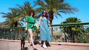 Two women holding hands walking their dog in The Gardens on El Paseo in Greater Palm Springs